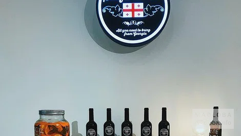Логотип магазина Gamarjoba Saqartvelo и стол для дегустации напитков