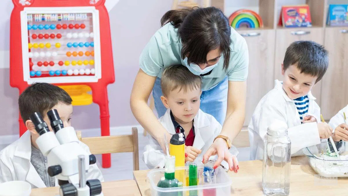 воспитатель занимается с детьми в саду Montessori