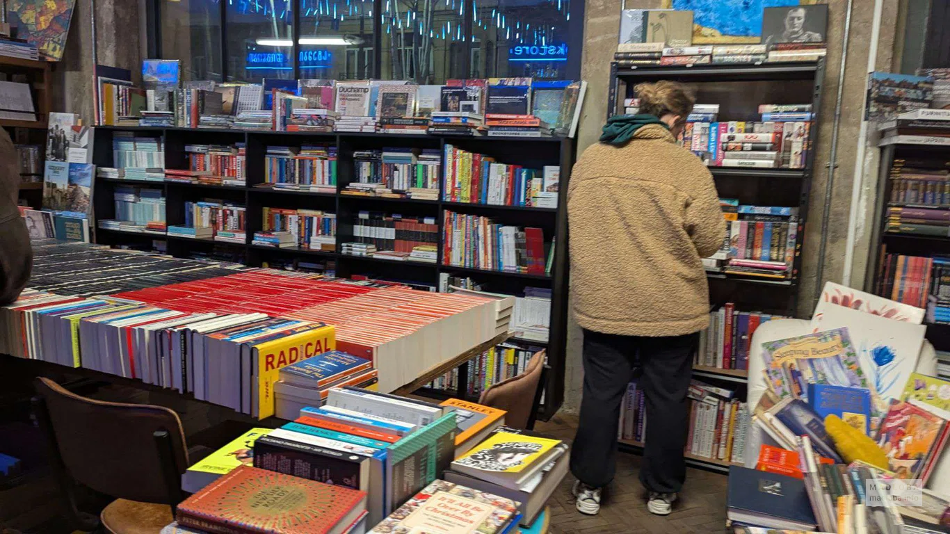 девушка смотрит книги в магазине Stamba Bookstore в Тбилиси