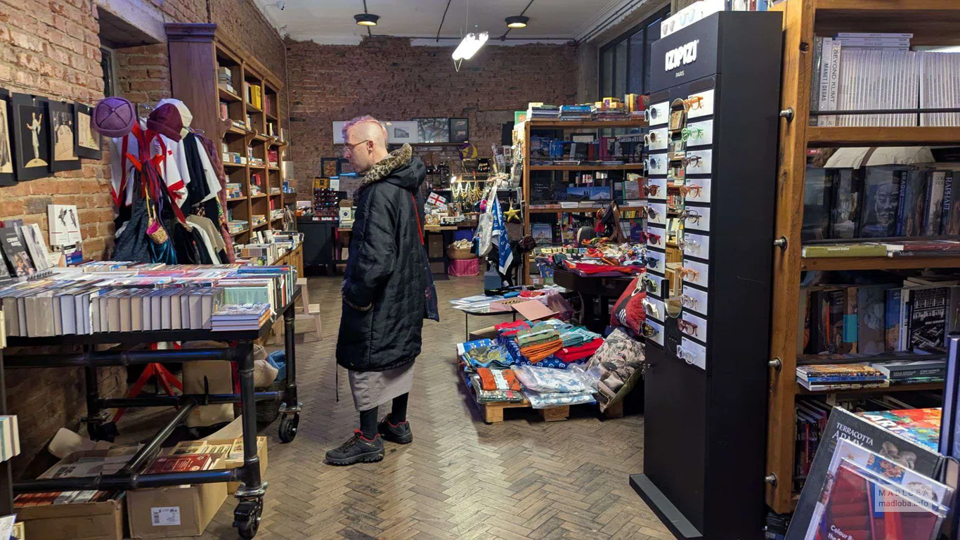 молодой человек выбирает книги в магазине Stamba Bookstore
