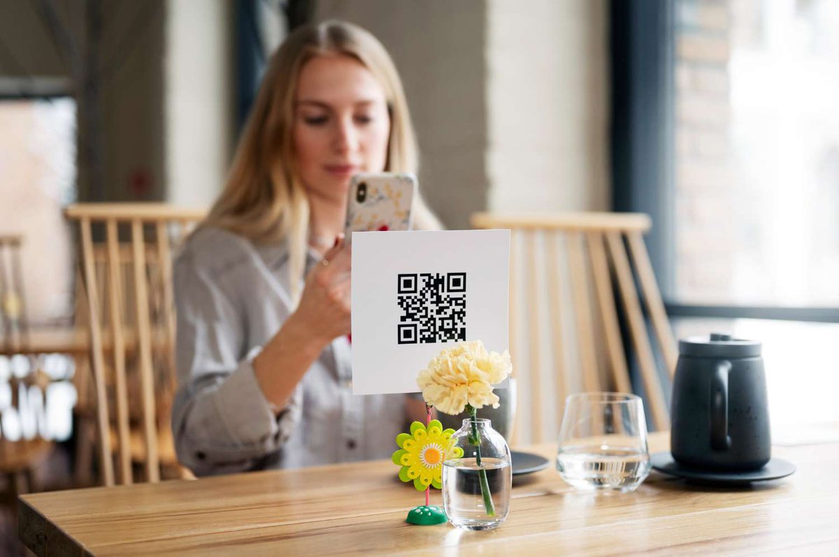 Женщина сканирует qr-код среднего размера в ресторане, чтобы оставить отзыв.jpg