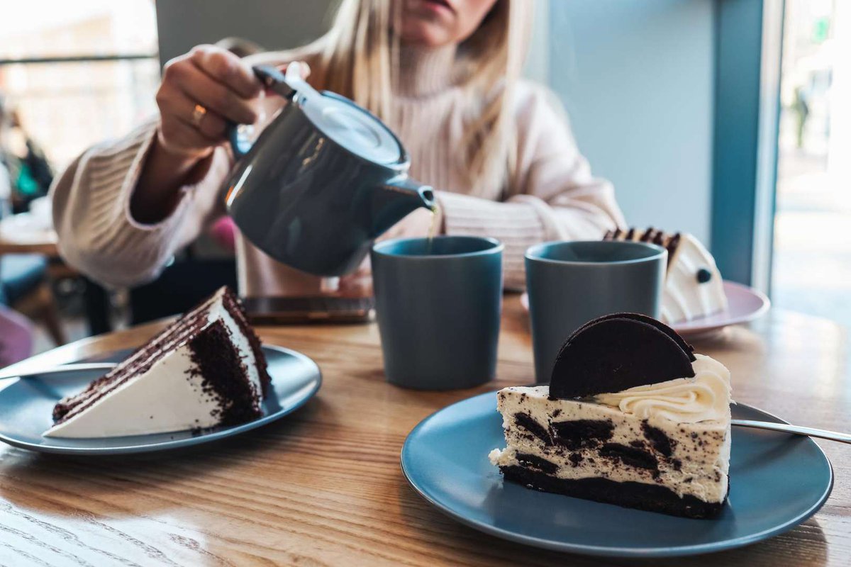 A girl in a cafe pours tea from a teapot