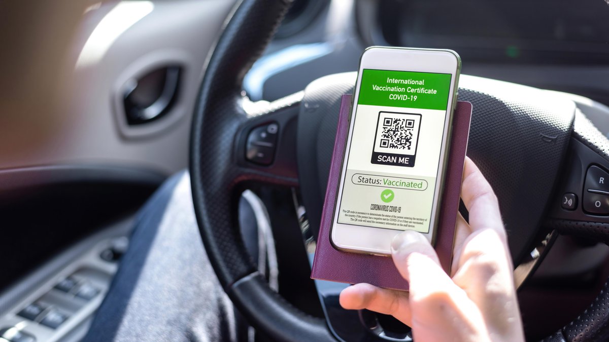 male-hand-holding-passport-smartphone-with-international-vaccination-certificate-covid-19-qr-code-car.jpg