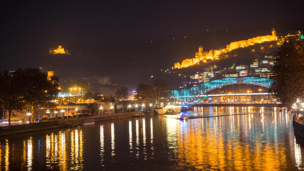 Night illumination of the bridge and river in Tbilisi