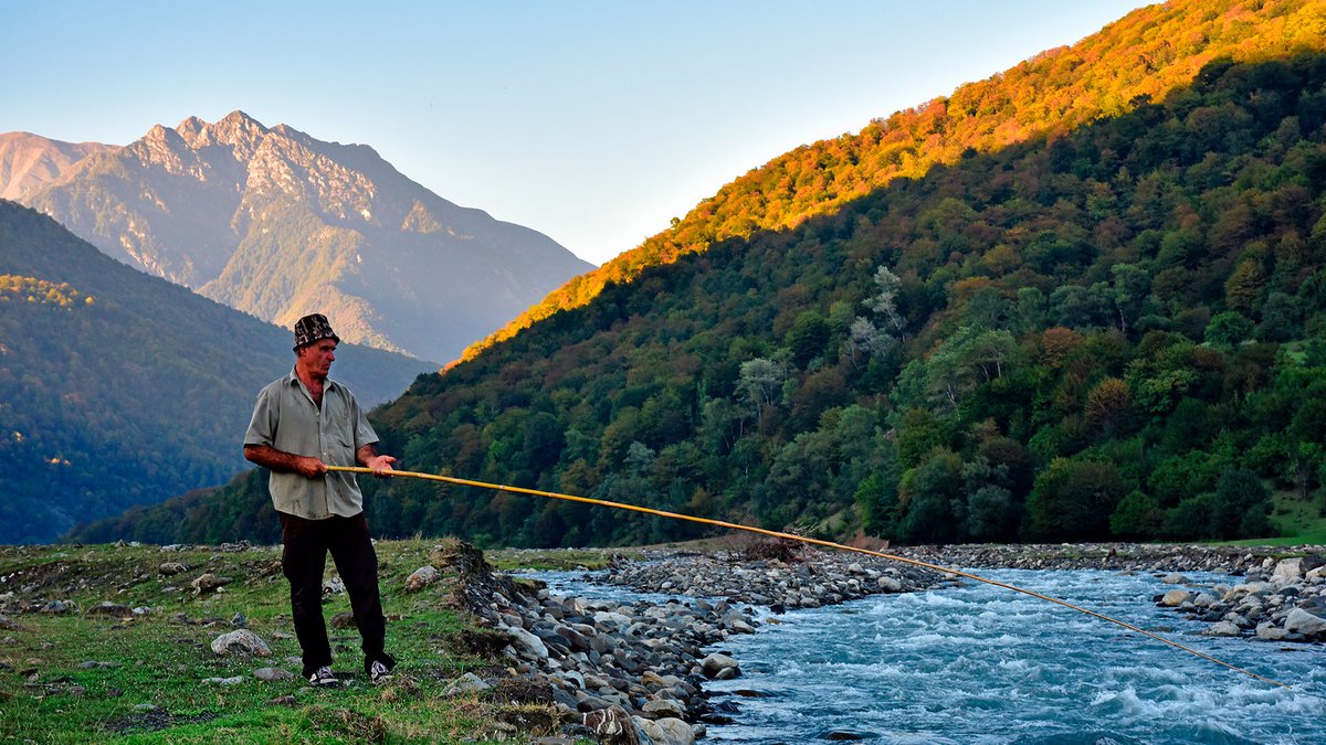 Fisherman with a fishing rod at the mountain river of Georgia